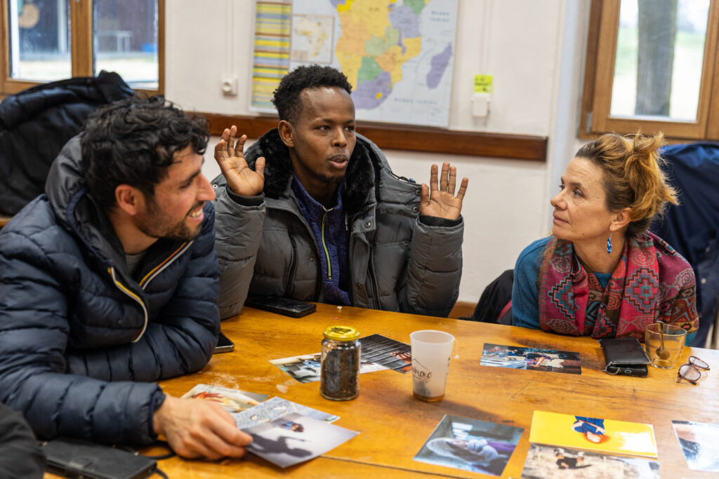 Trois personnes, deux hommes et une femme, sont installés autour d'une table. Ils participent à un atelier. 